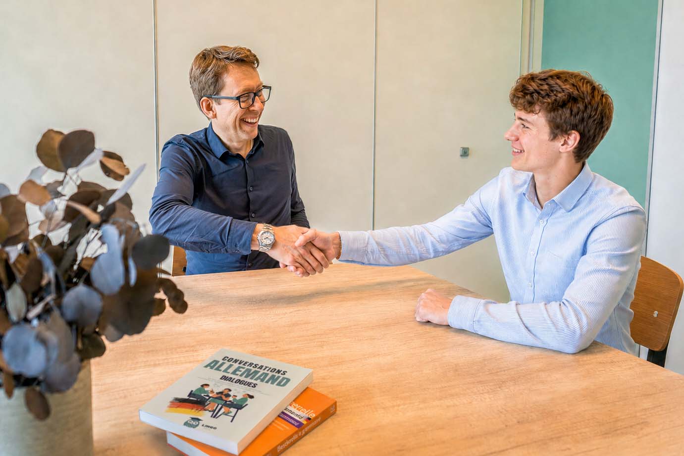 Daniel Schwenger und ein Schüler geben sich am Arbeitstisch die Hand.